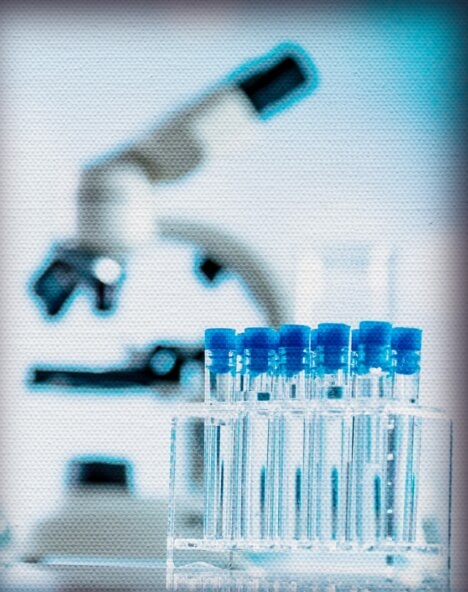 Test tubes in a rack on a table with a microscope