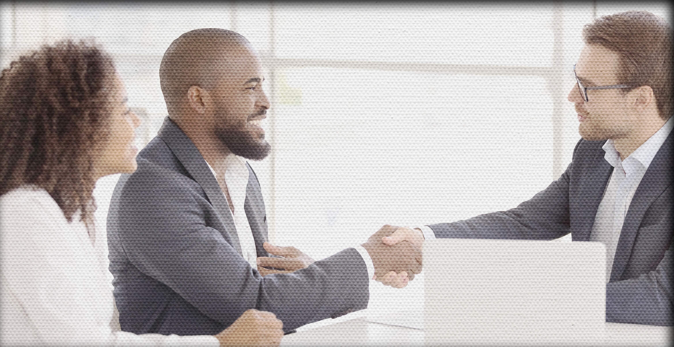 Couple smiling and shaking hands with another man over a deal